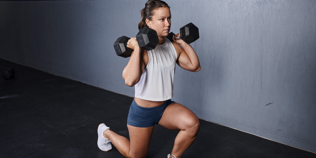 image of a lady going weighted lunges with the rubber dumbbells in a gym enviroment