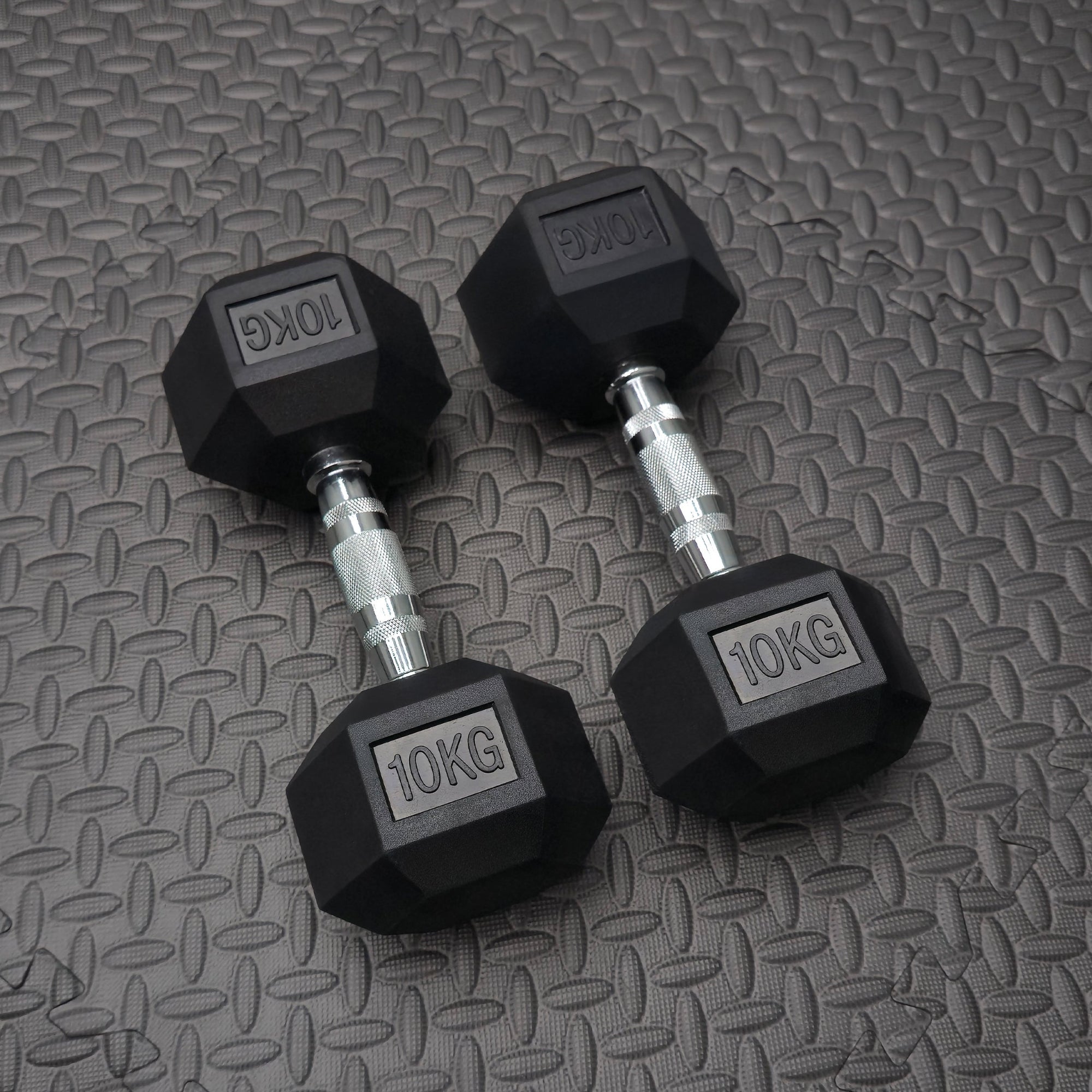 Pair of 10KG rubber dumbbells on a textured gray surface