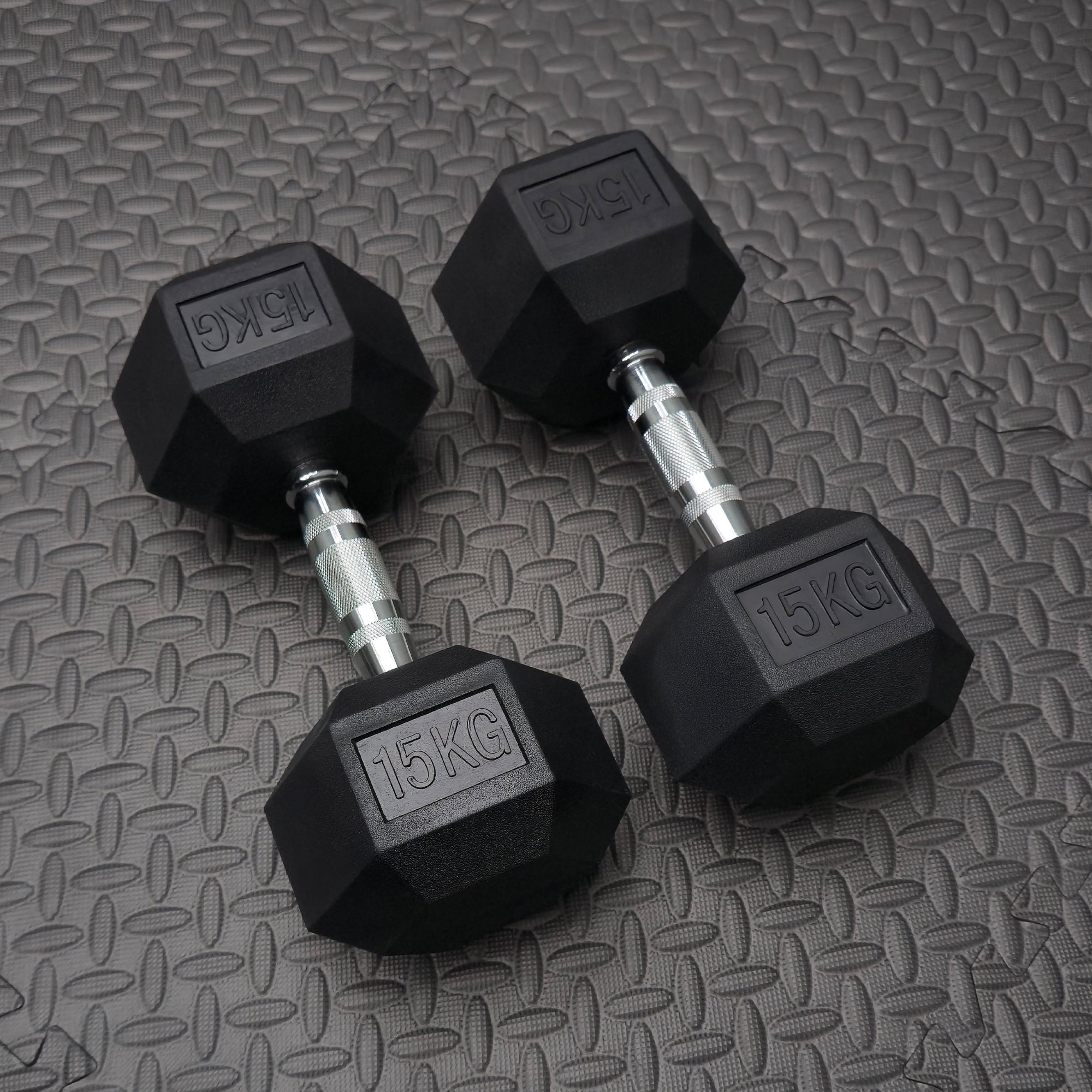 Pair of black dumbbells with '15KG' marking on a textured gray surface