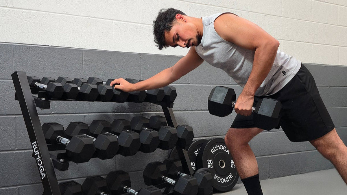 Man exercising with hex dumbbells in a garage 