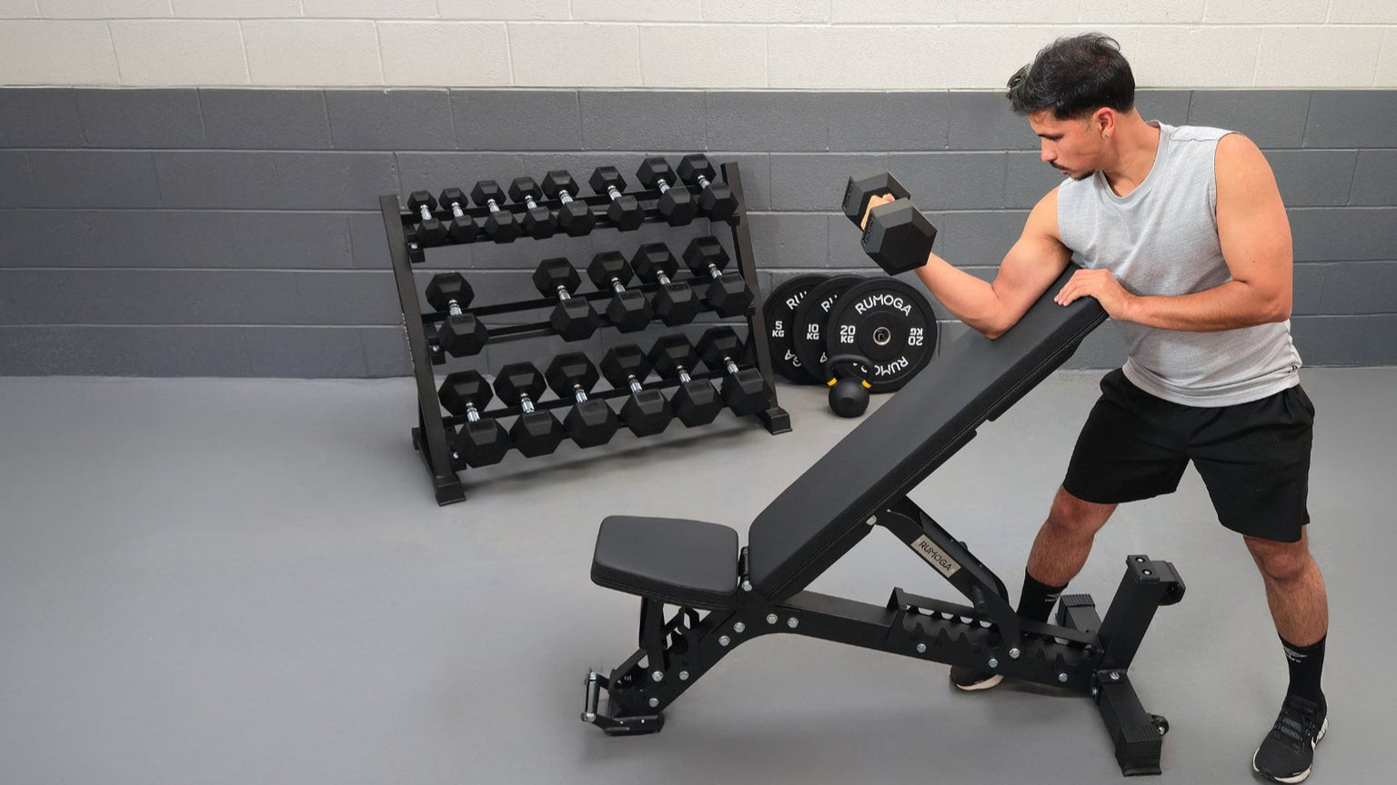 Man exercising with a weight bench in a gym setting with hex dumbbells 