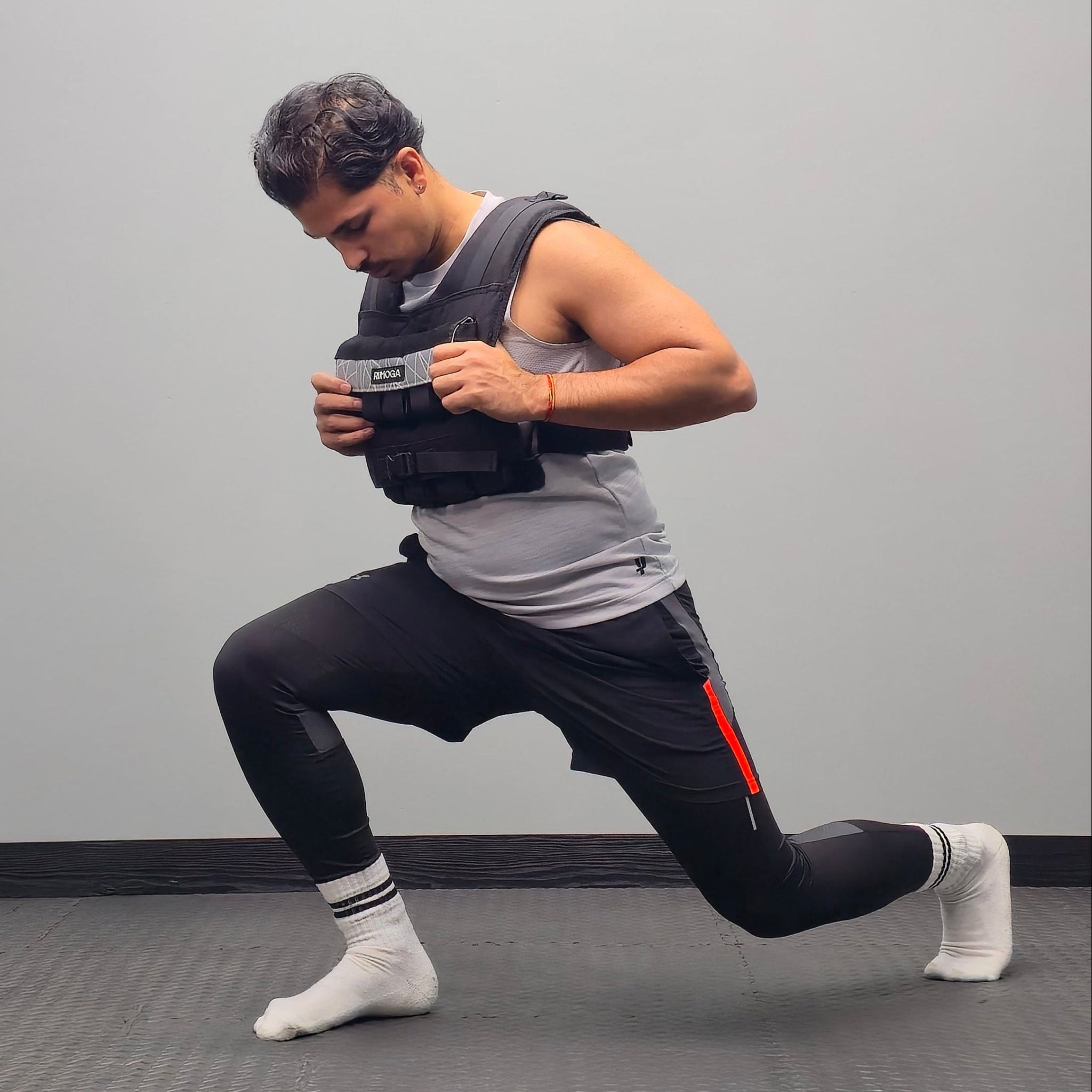 Man performing a lunge with a weighted vest on a grey background
