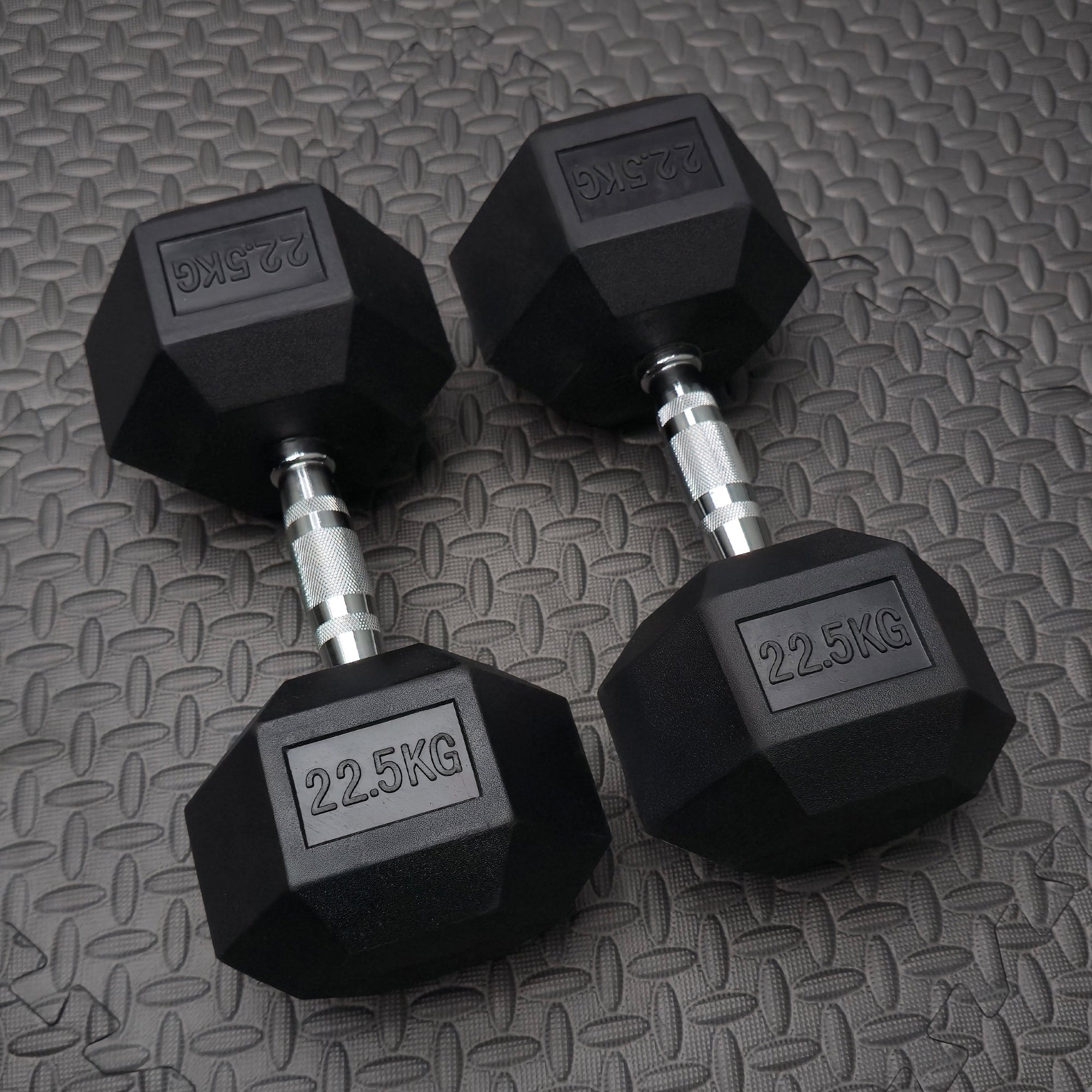 Pair of black dumbbells with '22.5KG' marking on a textured surface