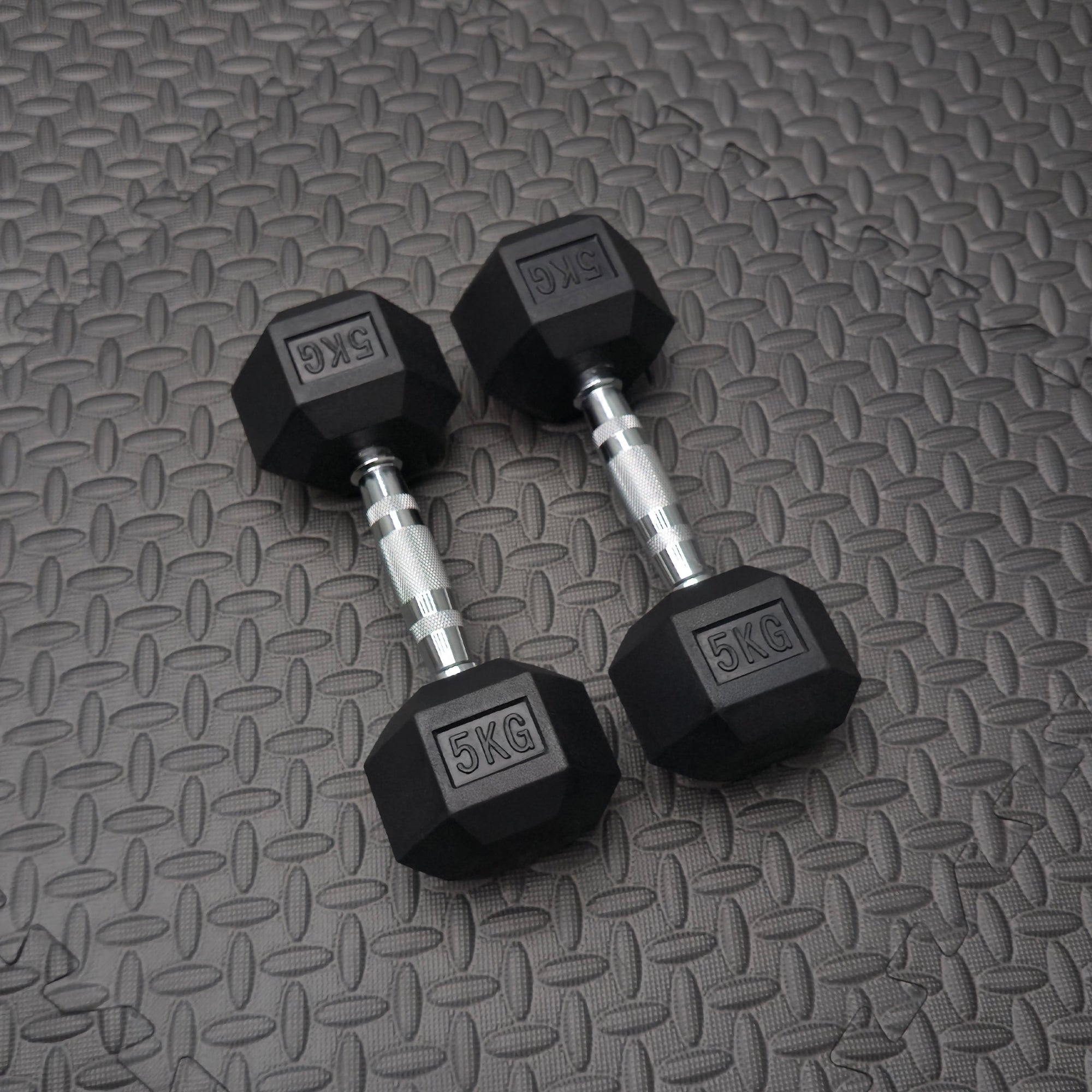 Pair of 5KG dumbbells on a textured gray surface